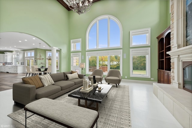 living room with plenty of natural light, a notable chandelier, a high ceiling, and decorative columns