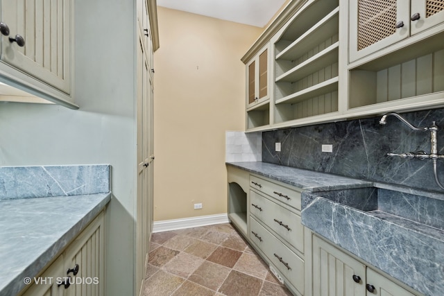 kitchen featuring decorative backsplash, light stone countertops, and cream cabinets