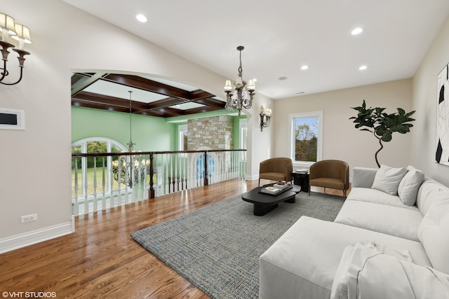 living room featuring beamed ceiling, wood-type flooring, an inviting chandelier, and coffered ceiling