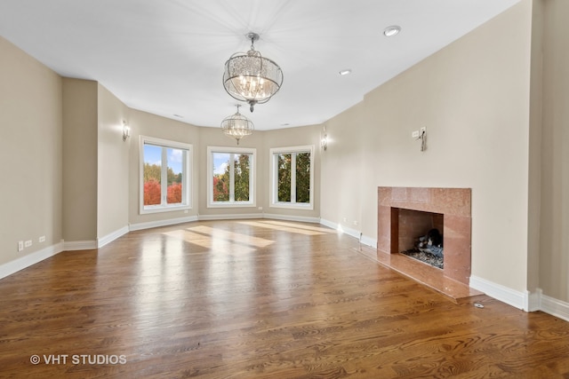 unfurnished living room with a fireplace, hardwood / wood-style flooring, and an inviting chandelier