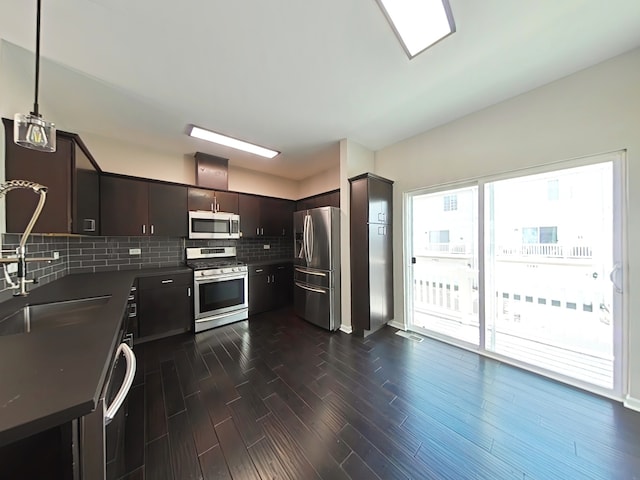 kitchen featuring decorative backsplash, appliances with stainless steel finishes, dark brown cabinets, sink, and pendant lighting