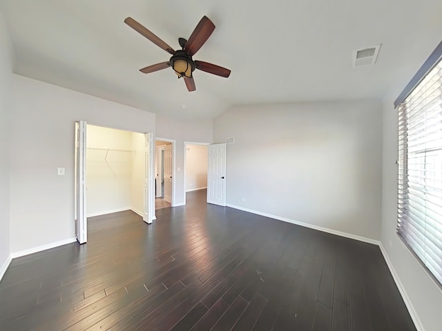 unfurnished bedroom featuring lofted ceiling, ceiling fan, dark hardwood / wood-style floors, a spacious closet, and a closet