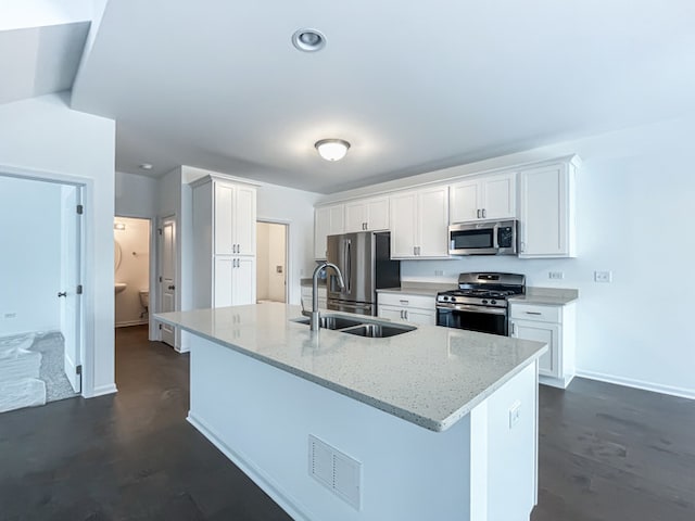 kitchen with a kitchen island with sink, white cabinetry, light stone counters, and stainless steel appliances