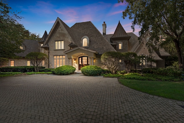french country home with stone siding, a chimney, and french doors