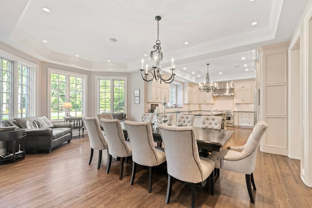 dining area featuring a tray ceiling, recessed lighting, a chandelier, wood finished floors, and crown molding