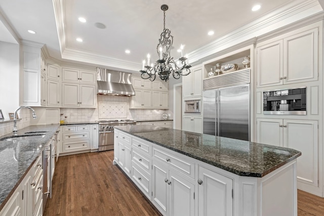 kitchen featuring open shelves, wall chimney range hood, a sink, a center island, and built in appliances