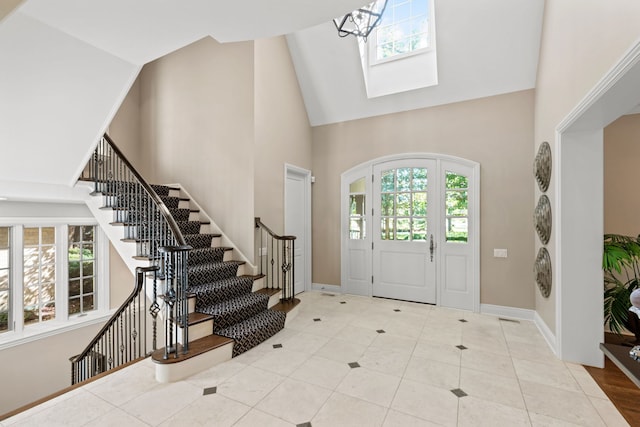 entryway with a wealth of natural light, stairs, a high ceiling, and baseboards
