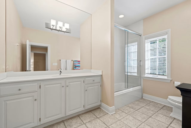 full bath featuring baseboards, toilet, vanity, and bath / shower combo with glass door