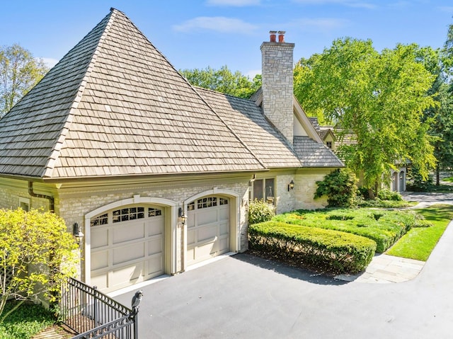 view of home's exterior featuring a garage, driveway, and a chimney
