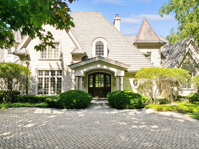 view of front facade with stone siding and a chimney
