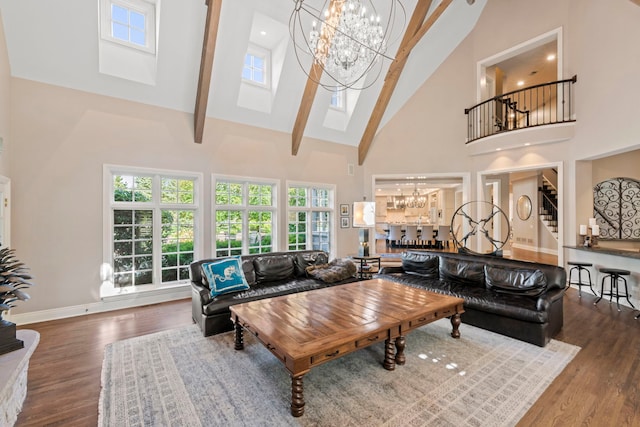 living area featuring a skylight, wood finished floors, an inviting chandelier, and high vaulted ceiling