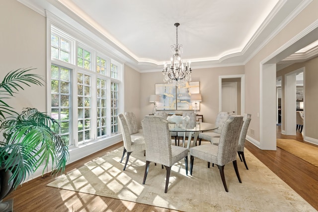 dining area featuring ornamental molding, a notable chandelier, a tray ceiling, and a healthy amount of sunlight