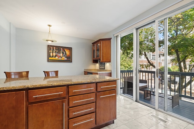 kitchen featuring a kitchen breakfast bar, light stone countertops, hanging light fixtures, and light tile patterned floors