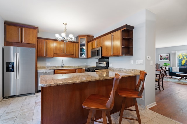 kitchen featuring kitchen peninsula, stainless steel appliances, light wood-type flooring, and pendant lighting