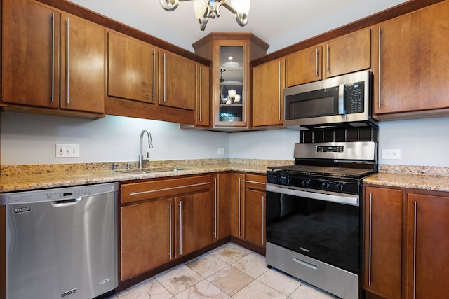 kitchen with light stone countertops, stainless steel appliances, and sink