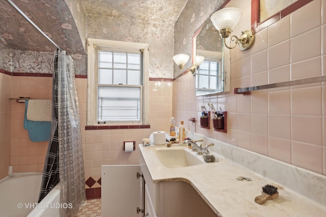 bathroom with vanity, a healthy amount of sunlight, tile walls, and shower / tub combo