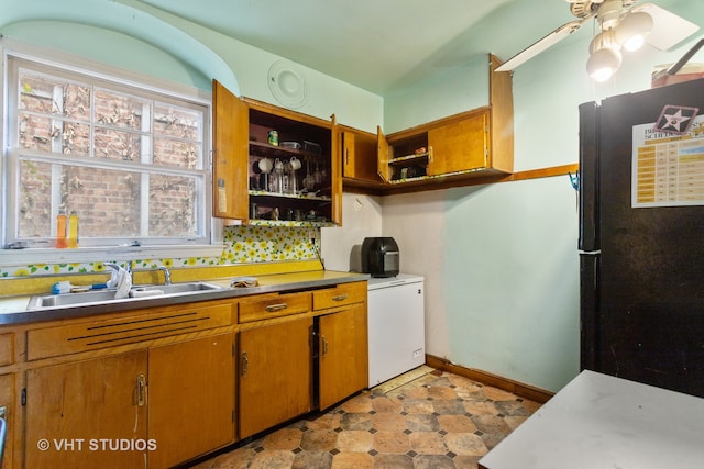 kitchen featuring decorative backsplash, black fridge, ceiling fan, and sink