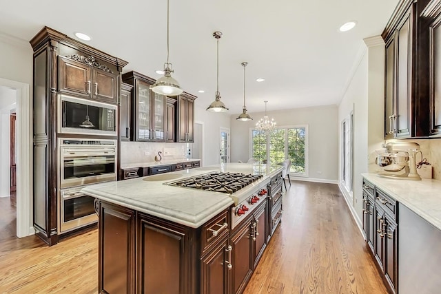 kitchen featuring decorative backsplash, stainless steel appliances, an inviting chandelier, light hardwood / wood-style floors, and hanging light fixtures