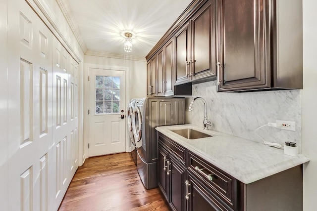 clothes washing area with sink, cabinets, washing machine and dryer, dark hardwood / wood-style floors, and crown molding