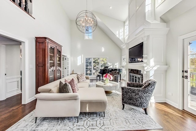 living room with a chandelier, a high end fireplace, high vaulted ceiling, and wood-type flooring