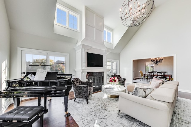 living room with a chandelier, a fireplace, high vaulted ceiling, and wood-type flooring