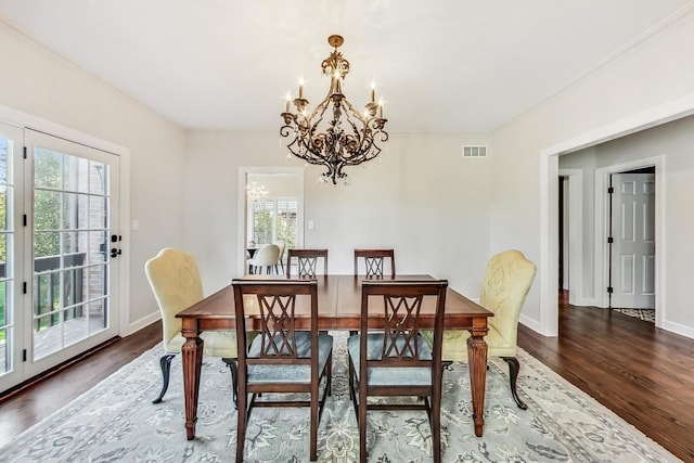 dining area featuring dark hardwood / wood-style floors, a healthy amount of sunlight, and an inviting chandelier