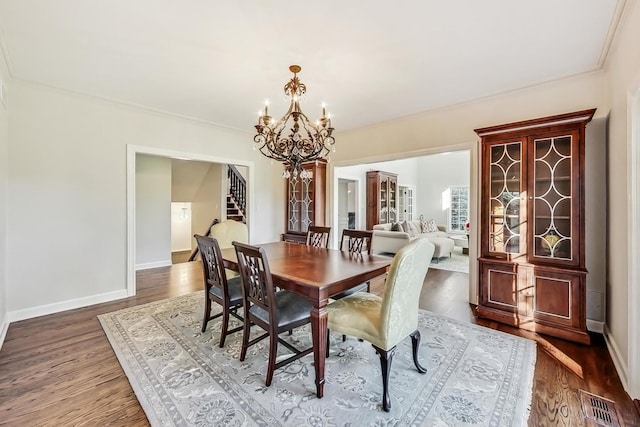 dining space featuring a chandelier, dark wood-type flooring, and ornamental molding