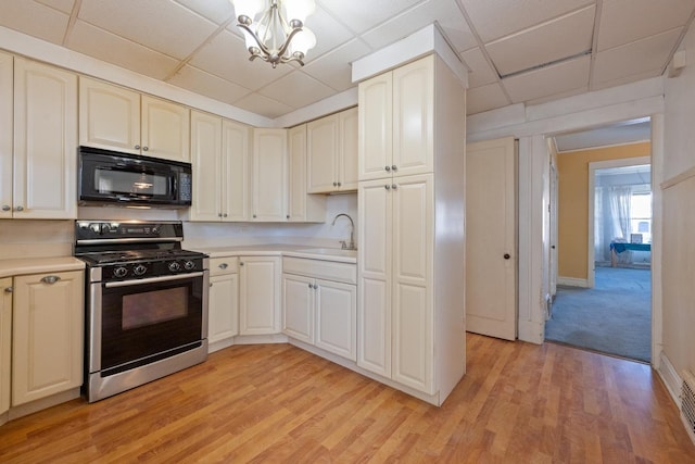 kitchen featuring sink, stainless steel range, a drop ceiling, and light hardwood / wood-style flooring