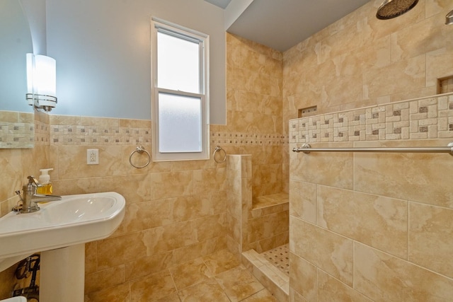 bathroom with a tile shower, tile walls, and sink