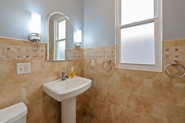 bathroom with sink, toilet, and tile walls