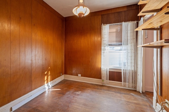 empty room with wooden walls and hardwood / wood-style floors