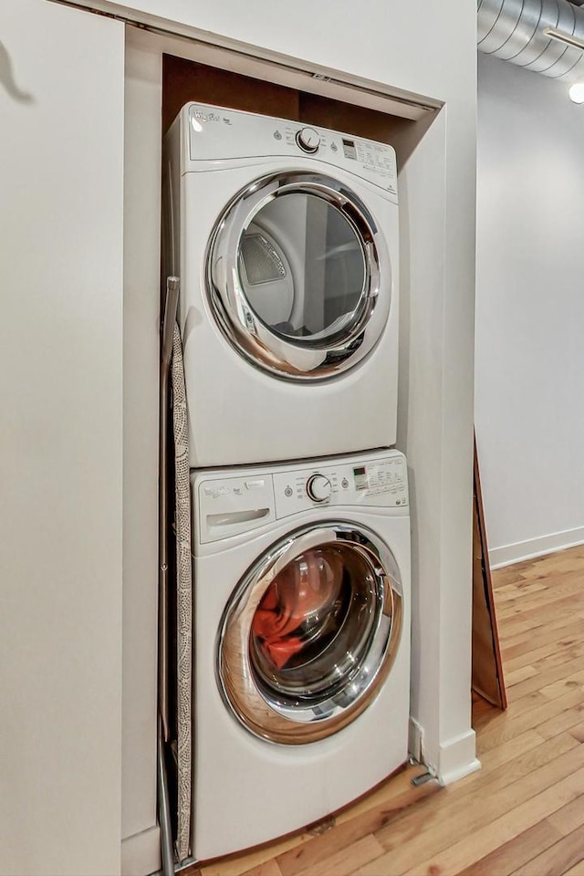 laundry room featuring light hardwood / wood-style flooring and stacked washer and clothes dryer