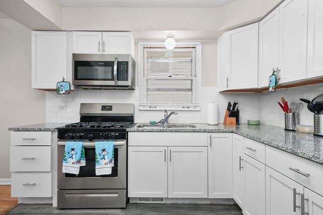 kitchen featuring light stone countertops, stainless steel appliances, dark wood-type flooring, sink, and white cabinets