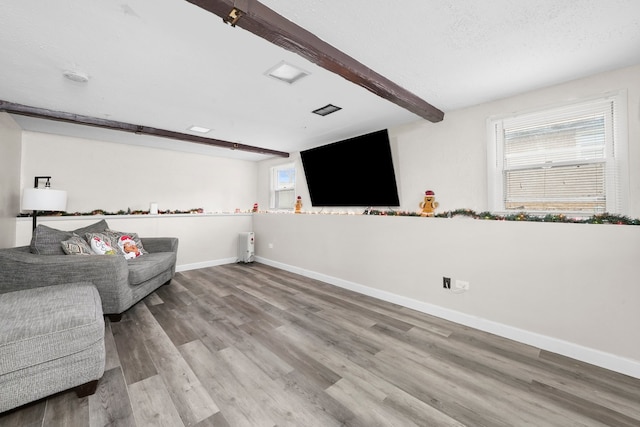 living area with hardwood / wood-style floors, beamed ceiling, and a textured ceiling