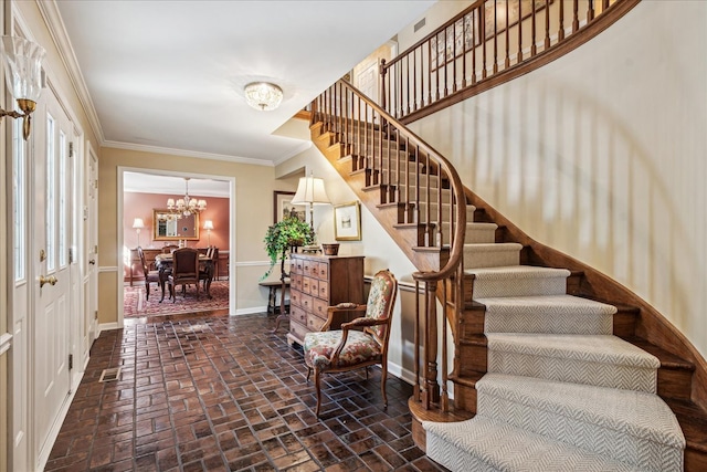 foyer with an inviting chandelier and ornamental molding