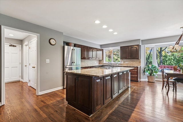 kitchen featuring stainless steel fridge, a center island, dark brown cabinetry, and dark wood-type flooring