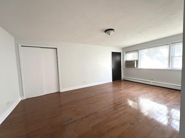 unfurnished bedroom featuring dark hardwood / wood-style flooring, cooling unit, and a baseboard heating unit