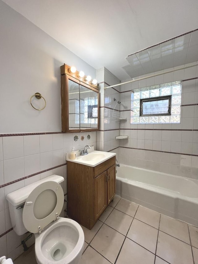 full bathroom with tile patterned floors, vanity, tiled shower / bath combo, tile walls, and toilet