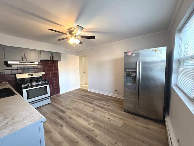 kitchen featuring crown molding, stainless steel fridge, gray cabinets, tasteful backsplash, and range with gas stovetop