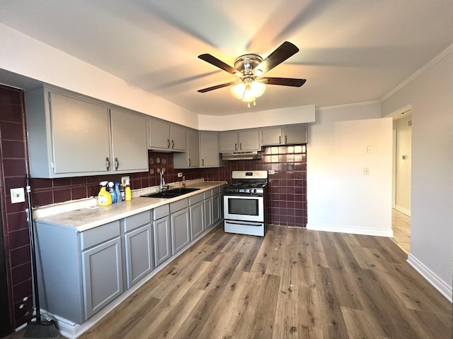 kitchen with backsplash, white gas range, gray cabinetry, sink, and hardwood / wood-style flooring