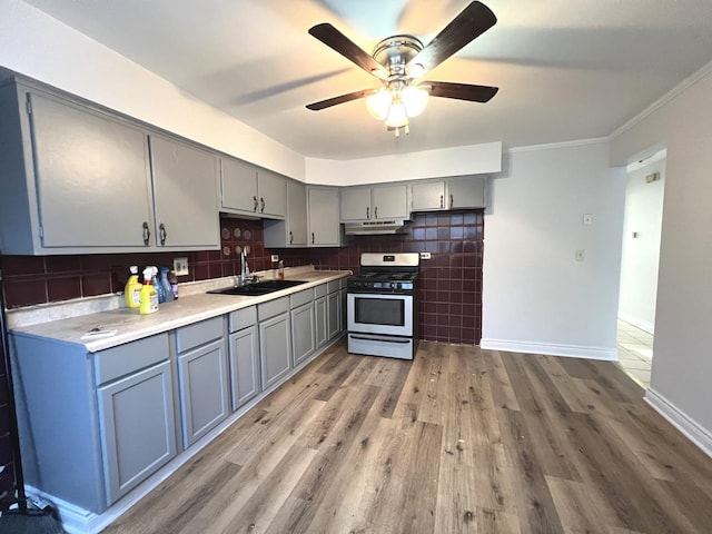 kitchen featuring tasteful backsplash, gas range oven, sink, hardwood / wood-style floors, and gray cabinets