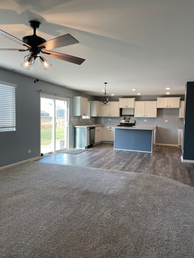 kitchen with appliances with stainless steel finishes, ceiling fan with notable chandelier, a kitchen island, hanging light fixtures, and white cabinets