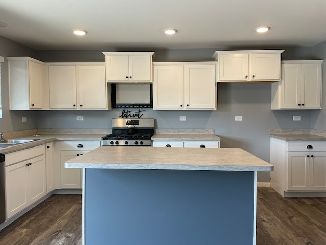 kitchen with appliances with stainless steel finishes, white cabinets, a kitchen island, and dark hardwood / wood-style flooring