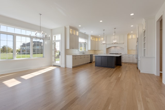 kitchen with a center island, hanging light fixtures, stainless steel appliances, and light hardwood / wood-style floors