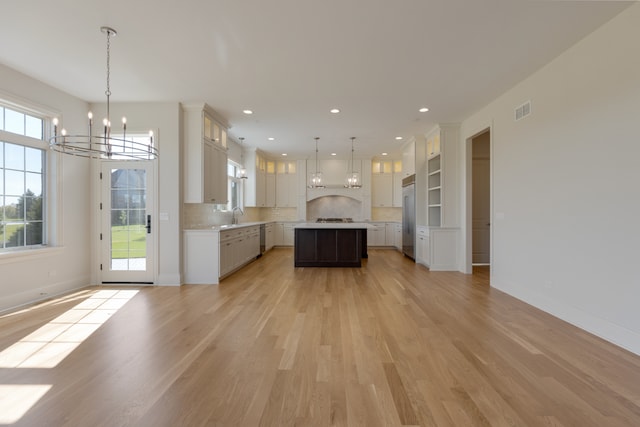 kitchen featuring stainless steel appliances, a healthy amount of sunlight, a kitchen island, and hanging light fixtures