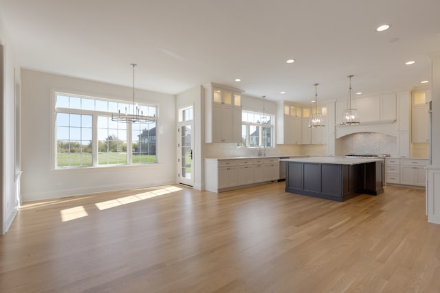 kitchen with a kitchen island, white cabinetry, light hardwood / wood-style flooring, and decorative light fixtures