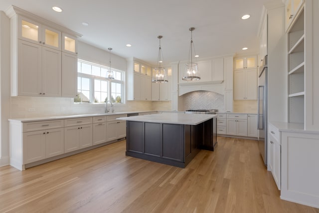 kitchen featuring light hardwood / wood-style flooring, a center island, decorative light fixtures, white cabinetry, and tasteful backsplash