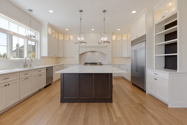 kitchen featuring backsplash, appliances with stainless steel finishes, light hardwood / wood-style flooring, pendant lighting, and a center island