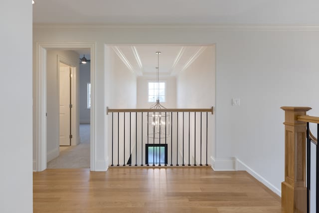 corridor featuring light hardwood / wood-style flooring, a chandelier, and crown molding