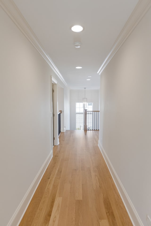 hall with light hardwood / wood-style flooring, a chandelier, and crown molding